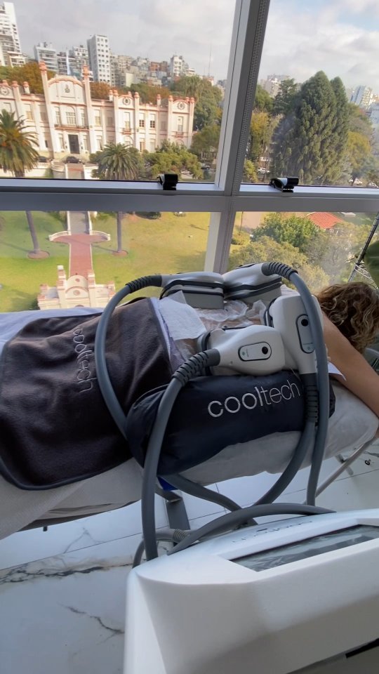 Sesión de criolipólisis Cooltech en la cabina, con el ventanal que da a un parque y a un edificio histórico